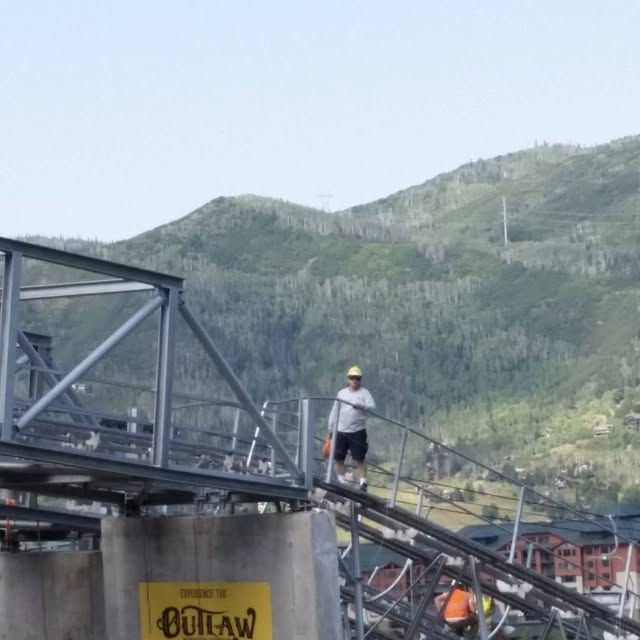 A worker in a hard hat on the elevated structure of the Outlaw Mountain Coaster at Steamboat Resort
