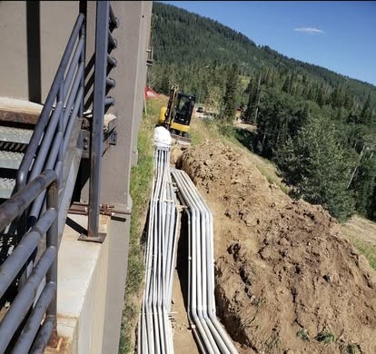 Gray PVC conduits running out of a hillside trench up to steel framing