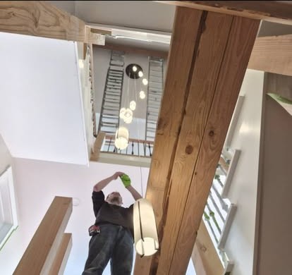 An electrician installing a cluster of glass globe pendant lights in a home stairwell