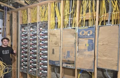 Bundles of cable fanning out to a wall of electrical panels during rough-in
