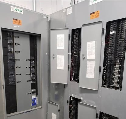 A commercial electrical room with several open panelboards on the wall