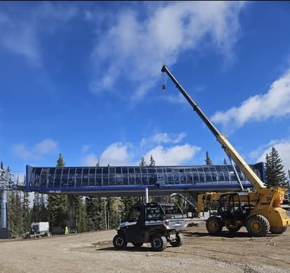 A ski-resort chairlift terminal under construction with a crane lifting components